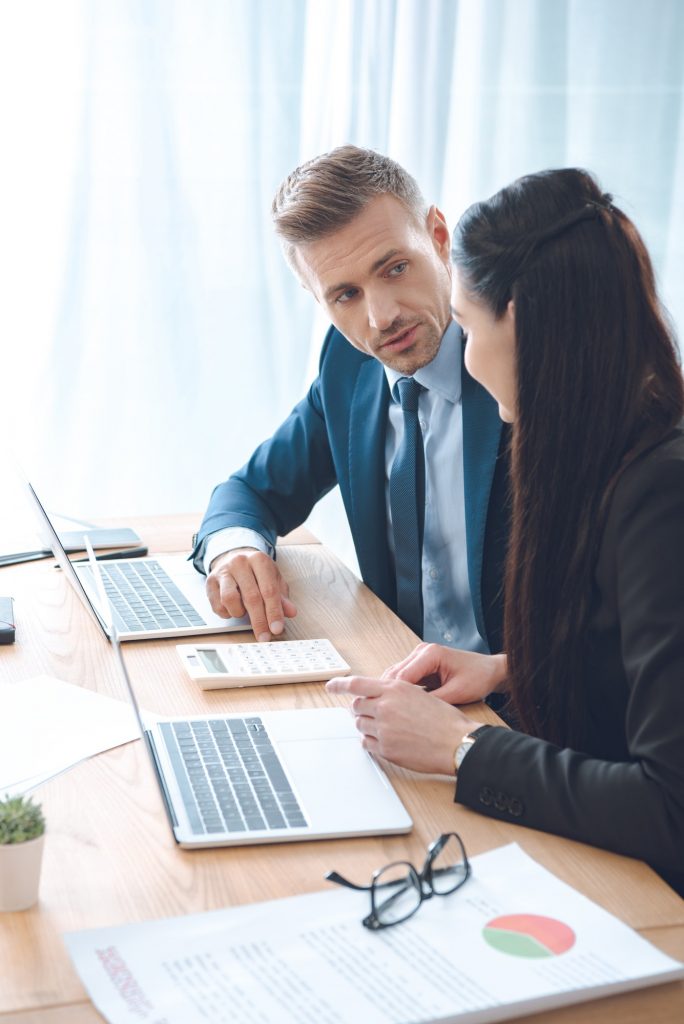 side view of businesspeople working at workplace with laptop in office