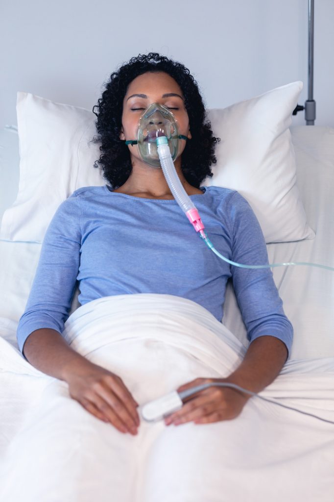 Sleeping african american female patient in hospital bed with oxygen ventilator