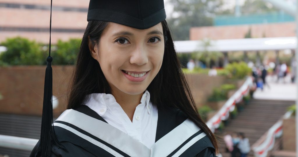 Woman wearing graduation gown in university